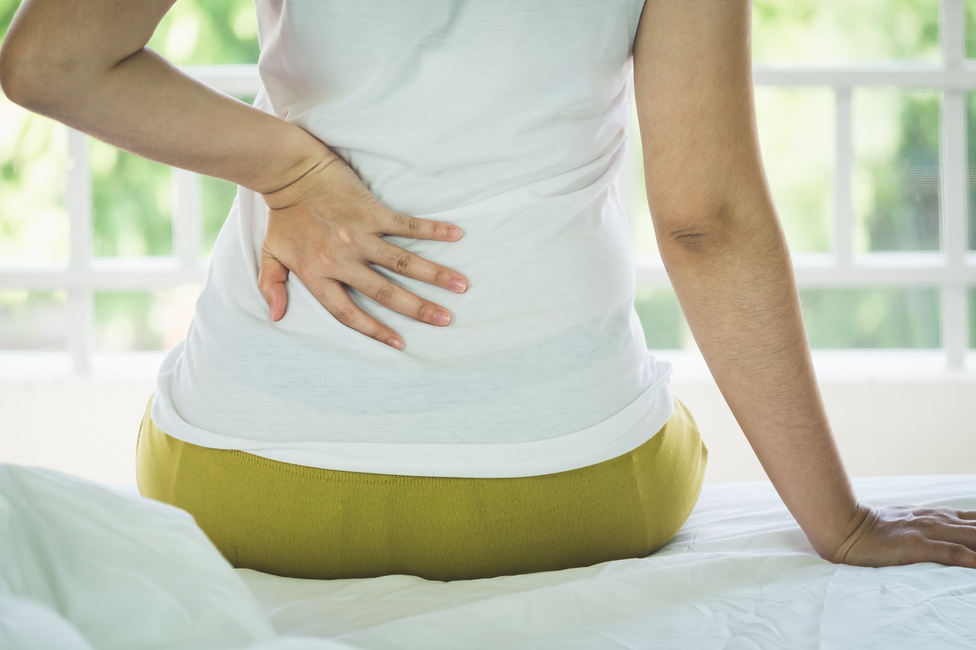 Closeup of Young Woman Suffering from Pain Back While Sitting on